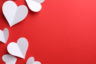 Photo of White paper hearts on red background, flat lay. Space for text