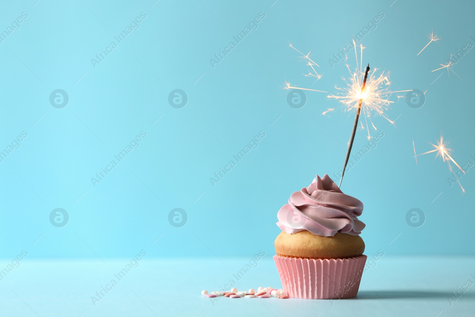 Photo of Delicious birthday cupcake with burning sparkler and space for text on color background