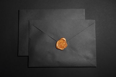 Photo of Envelopes with wax seal on black background, top view