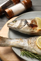 Photo of Delicious baked fish, lemon and rosemary on table, closeup