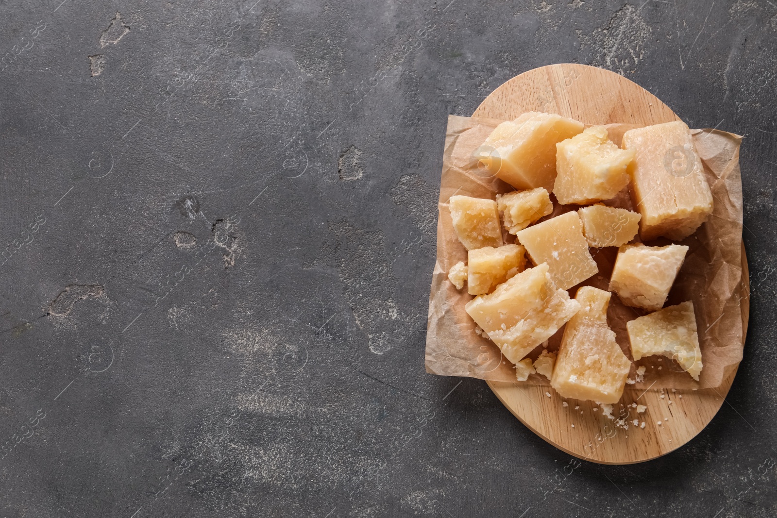 Photo of Pieces of delicious parmesan cheese on grey table, top view. Space for text