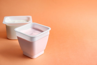 Plastic cups with tasty yogurt on color background