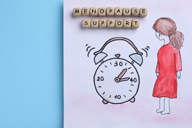 Drawing of woman figure near alarm clock and wooden cubes with words Menopause Symptoms on light blue background, top view