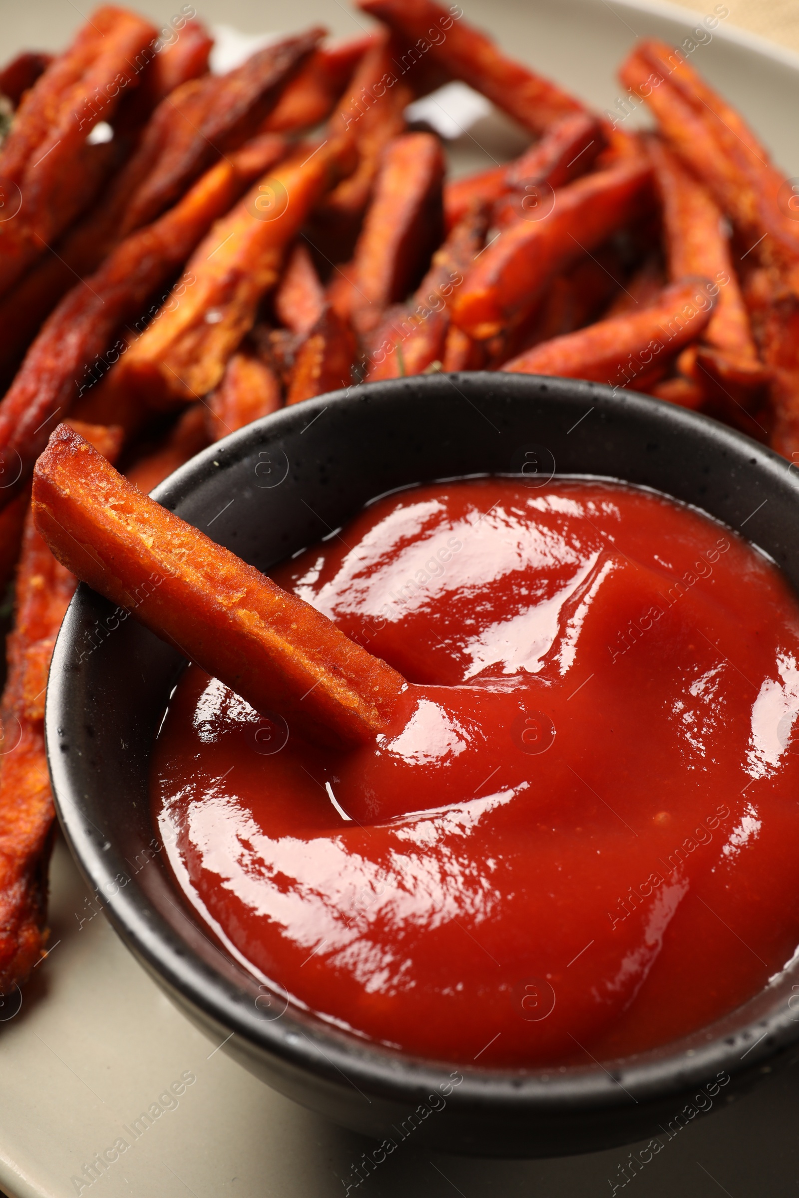 Photo of Sweet tasty potato fries and ketchup on plate, closeup