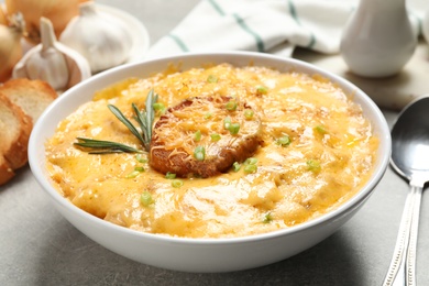 Tasty homemade French onion soup on grey table, closeup