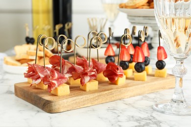 Photo of Different tasty canapes on white marble table, closeup