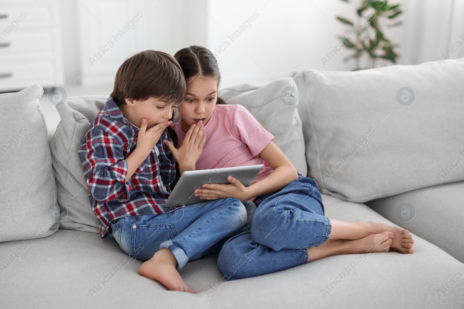 Photo of Happy brother and sister with tablet on sofa at home