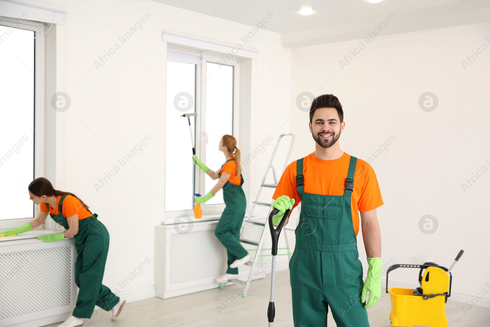 Photo of Team of professional janitors in uniforms cleaning room