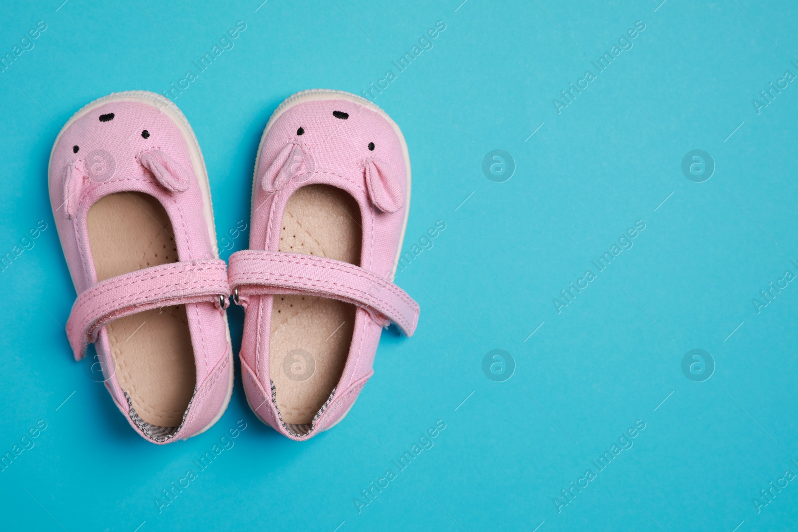 Photo of Cute baby shoes on light blue background, flat lay. Space for text