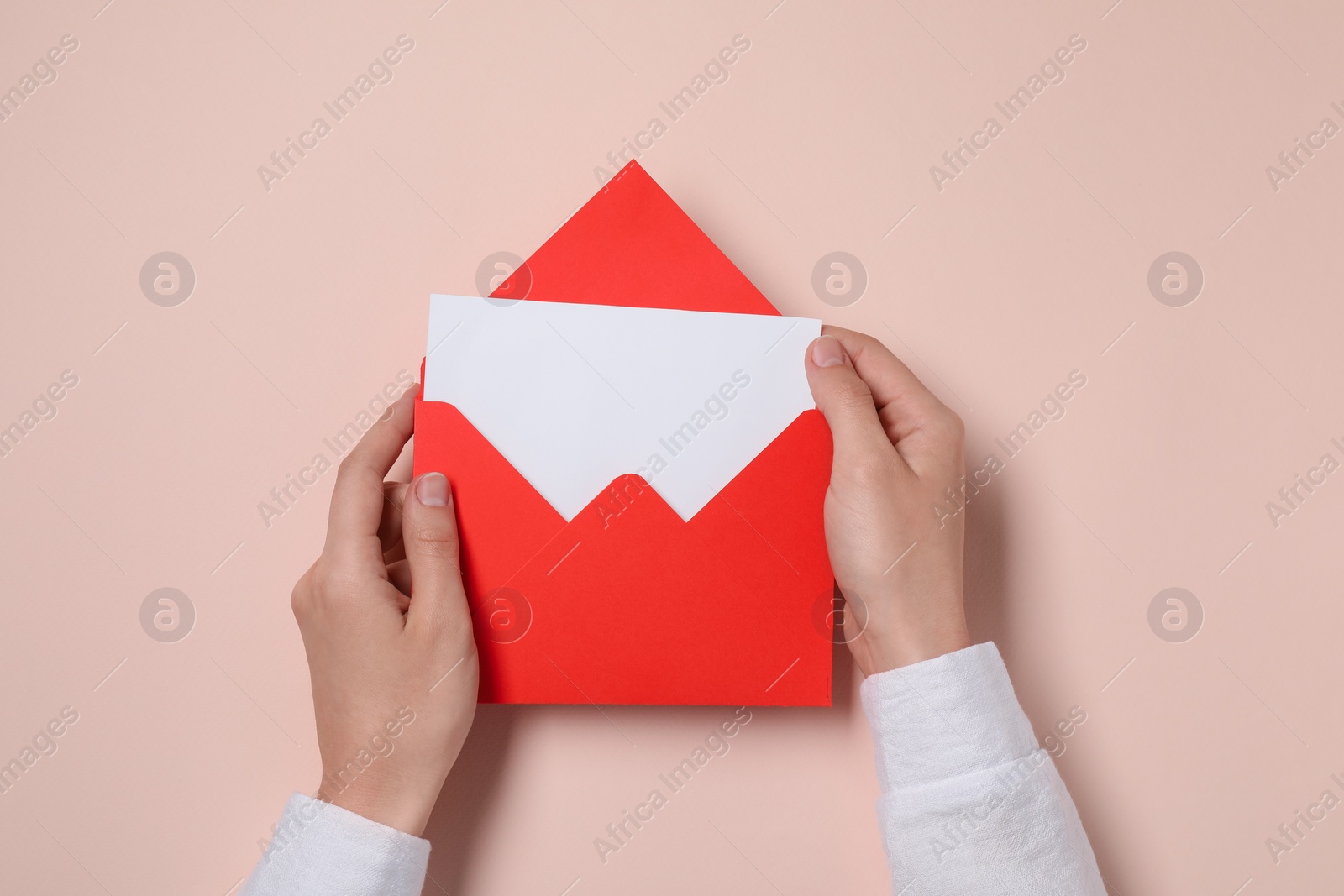 Photo of Woman with letter envelope and card at beige table, top view