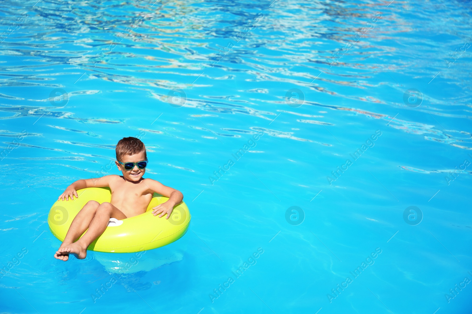 Photo of Little boy on inflatable ring in swimming pool