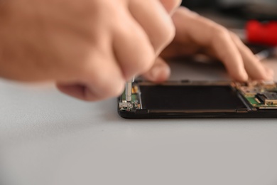 Technician repairing mobile phone at table, closeup