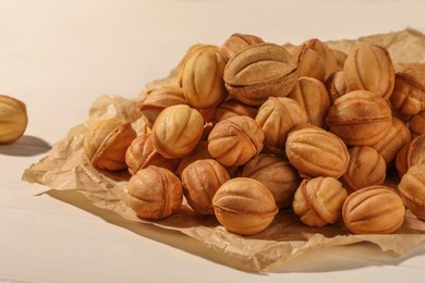 Freshly baked walnut shaped cookies on white wooden table, closeup. Homemade pastry filled with caramelized condensed milk