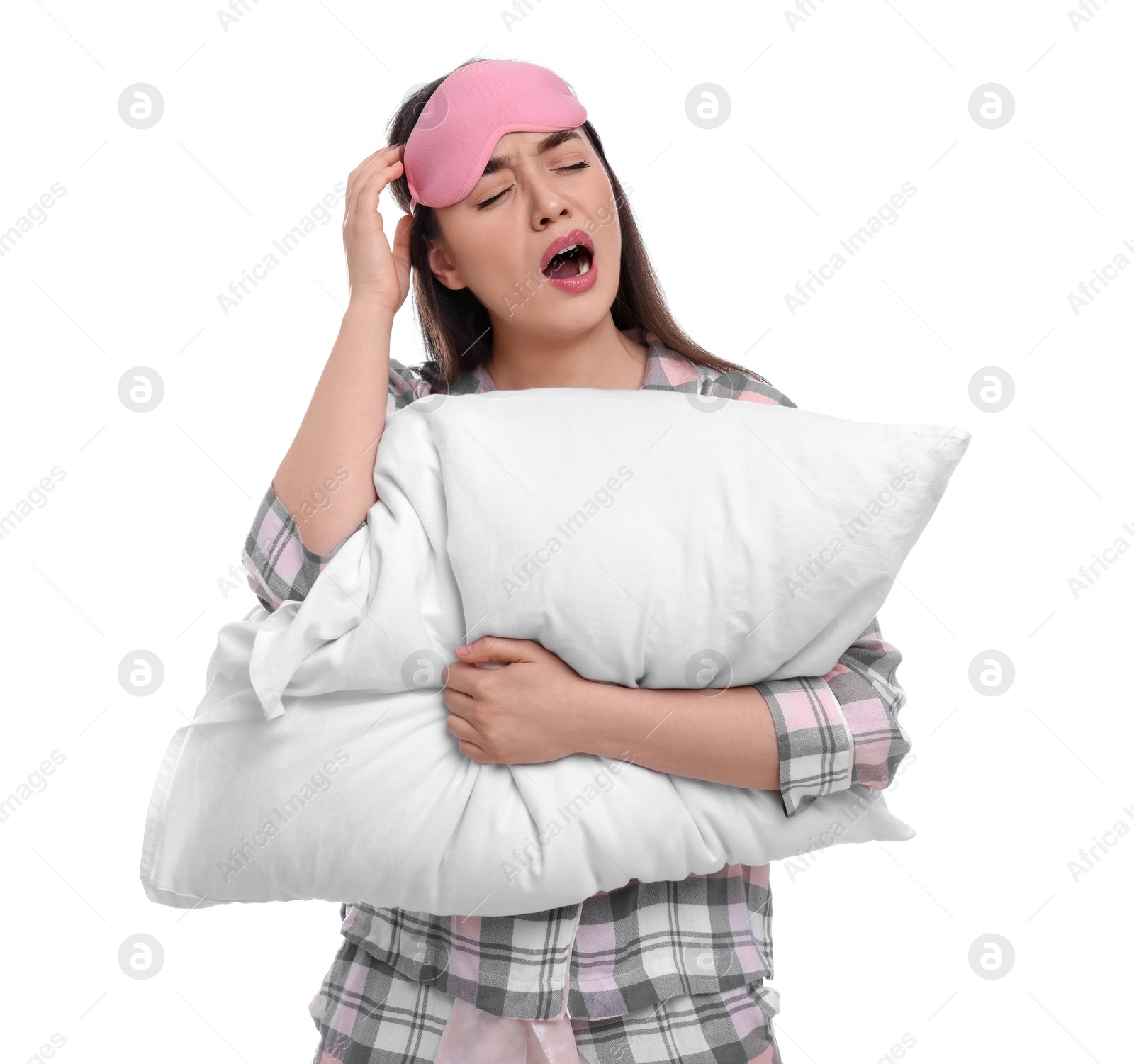 Photo of Tired young woman with sleep mask and pillow yawning on white background. Insomnia problem