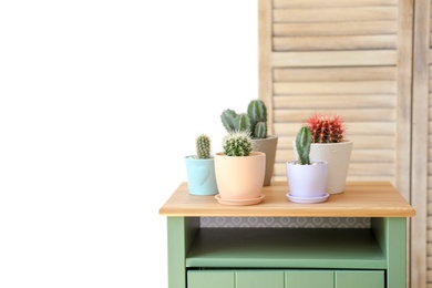 Photo of Beautiful different cacti in pots on table