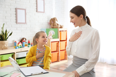 Speech therapist working with little girl in office