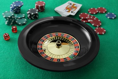 Roulette wheel, playing cards, chips and dice on green table, closeup. Casino game