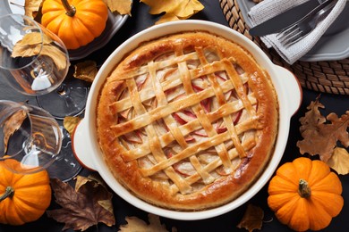 Photo of Delicious homemade apple pie and autumn decor on black table, flat lay. Thanksgiving Day celebration