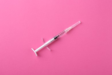 Photo of Injection cosmetology. One medical syringe on pink background, top view