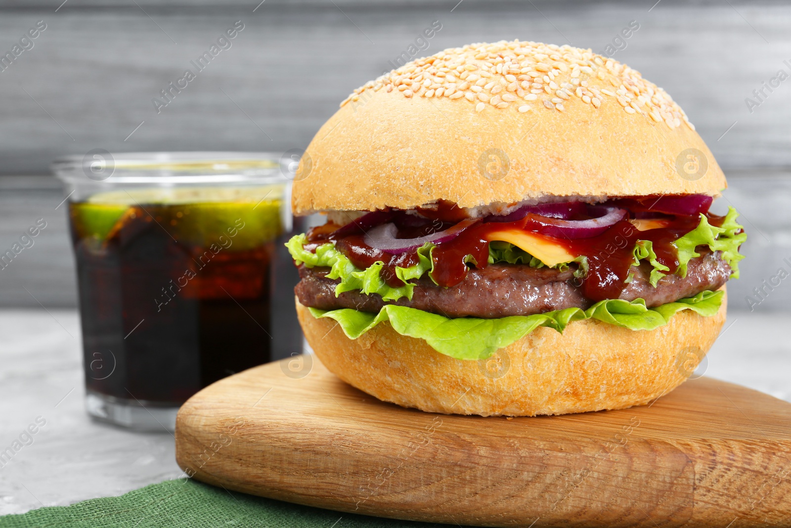 Photo of Delicious cheeseburger and drink on grey table, closeup