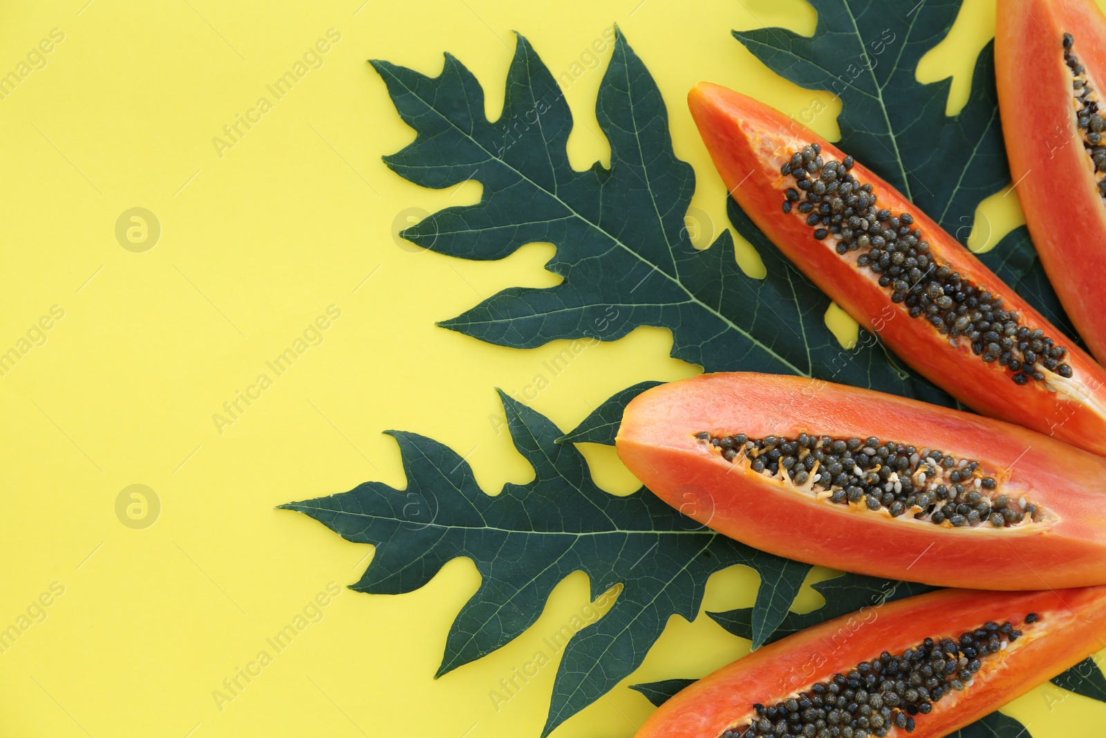 Photo of Fresh ripe papaya slices and leaf on yellow background, flat lay. Space for text