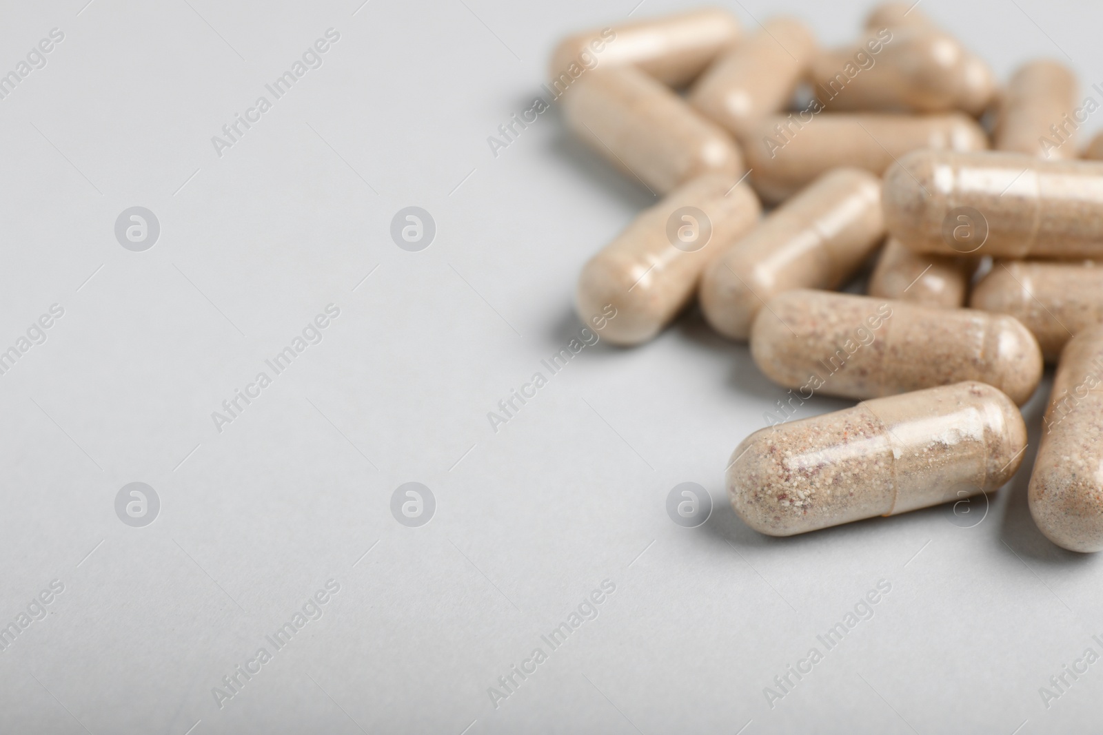 Photo of Many transparent gelatin capsules on light grey background, closeup. Space for text