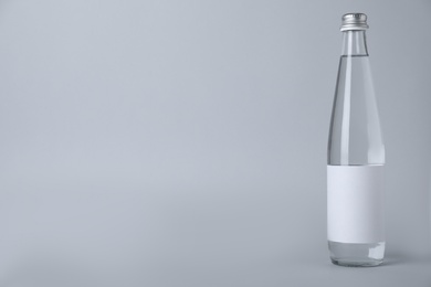 Photo of Glass bottle with soda water on light background. Space for text