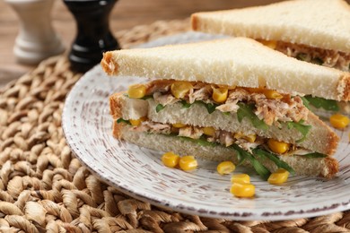 Photo of Delicious sandwiches with tuna, corn and greens on wicker mat, closeup