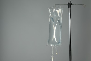 IV infusion set on pole against grey background. Space for text