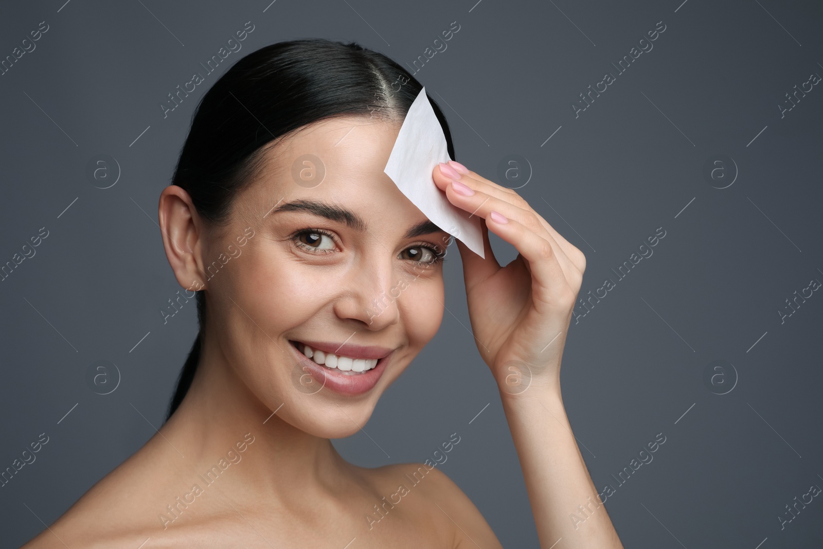 Photo of Beautiful woman using mattifying wipe on grey background