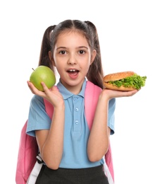 Photo of Surprised girl with burger and apple on white background. Healthy food for school lunch