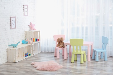 Photo of Cozy kids room interior with table, chairs and toys