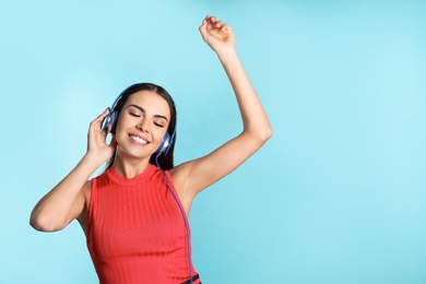 Photo of Attractive young woman enjoying music in headphones on color background. Space for text