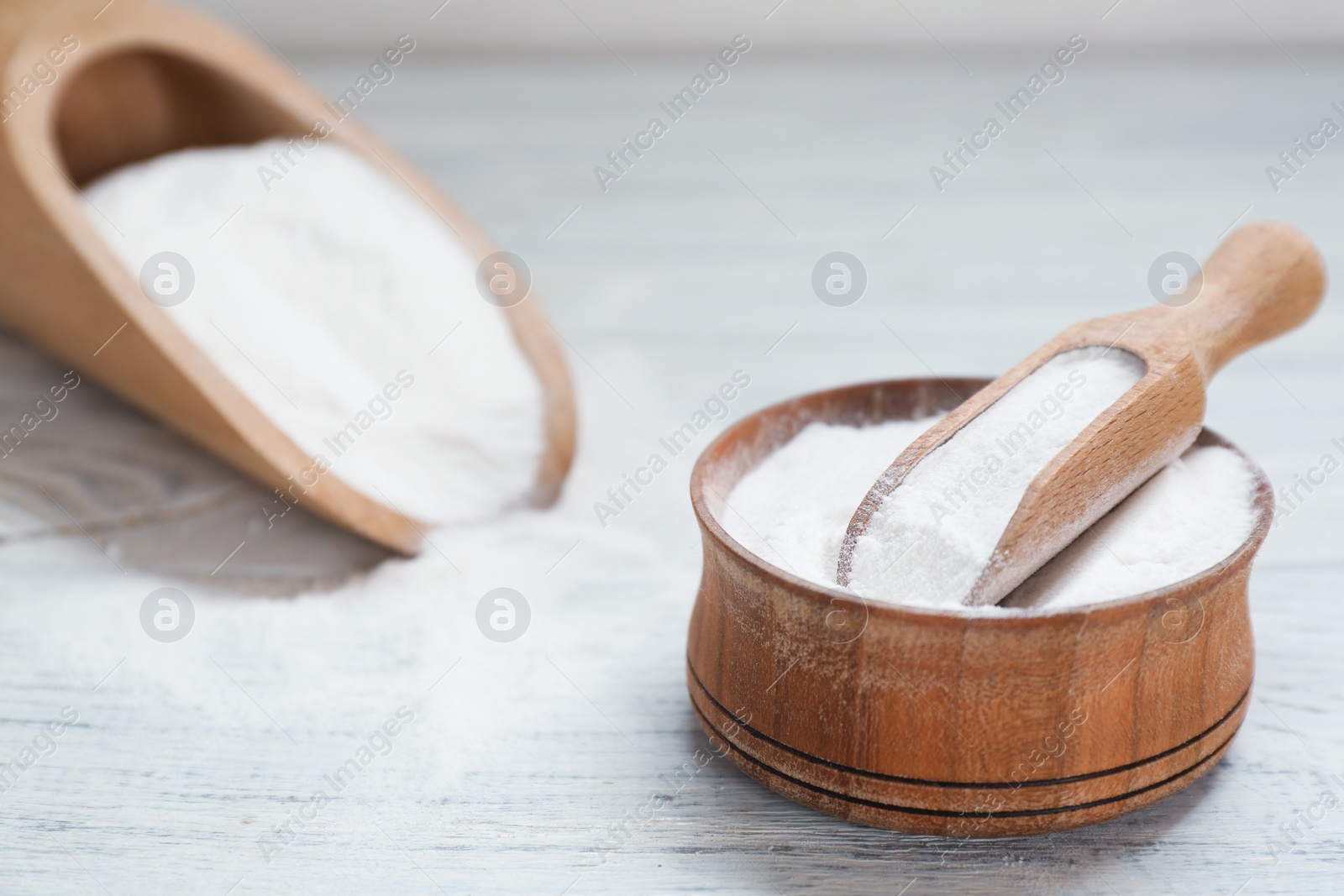 Photo of Bowl and scoop with baking soda on white wooden table