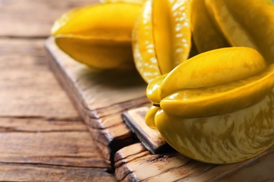 Photo of Delicious fresh carambola fruits on wooden table, closeup