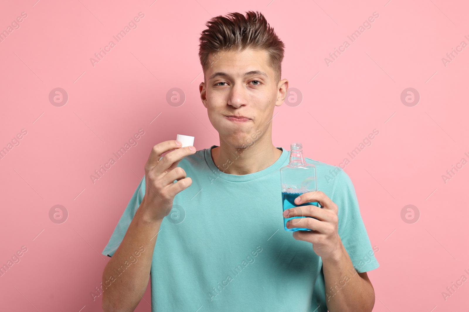 Photo of Young man using mouthwash on pink background