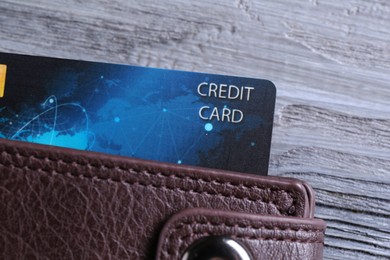 Photo of Credit card in leather wallet on grey wooden table, top view