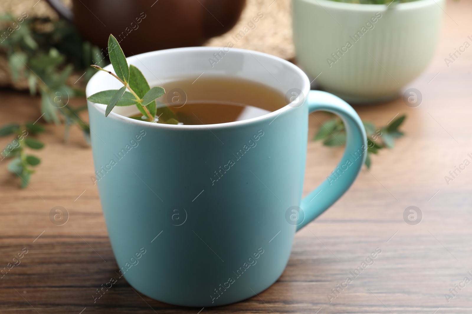 Photo of Cup of aromatic eucalyptus tea on wooden table, closeup