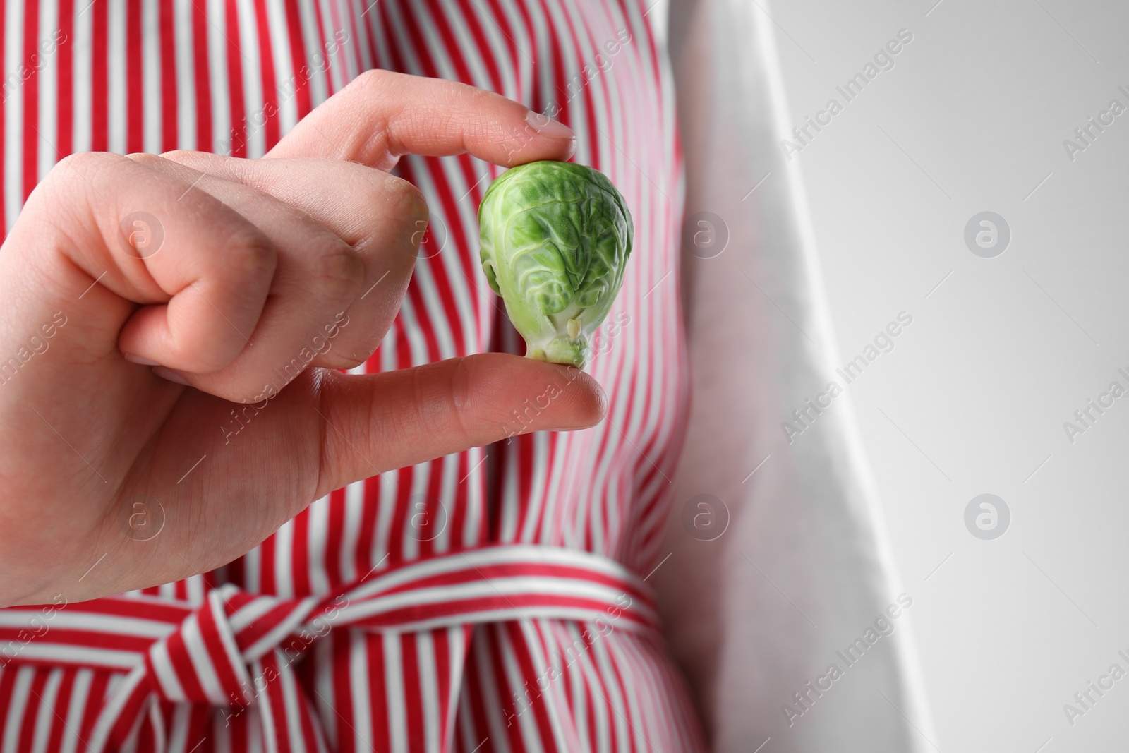 Photo of Woman showing fresh brussel sprout on white background, closeup