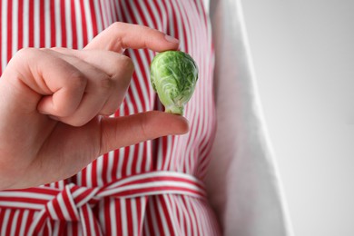 Photo of Woman showing fresh brussel sprout on white background, closeup