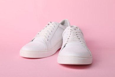 Photo of Pair of stylish white sneakers on pink background