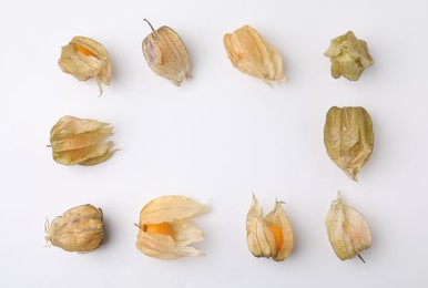 Frame of ripe physalis fruits with calyxes on white background, flat lay. Space for text