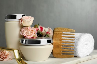 Hair care cosmetic products, beautiful flowers, comb and towel on white table