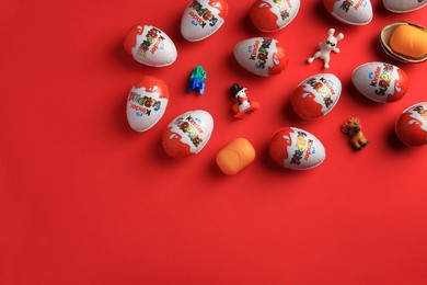 Sveti Vlas, Bulgaria - June 27, 2023: Kinder Surprise Eggs, plastic containers and toys on red background, flat lay. Space for text