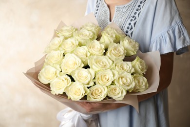 Woman holding luxury bouquet of fresh roses on light background, closeup