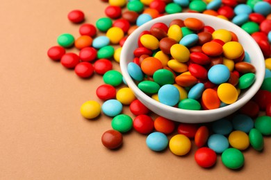 Photo of Tasty colorful candies on light brown background, closeup. Space for text