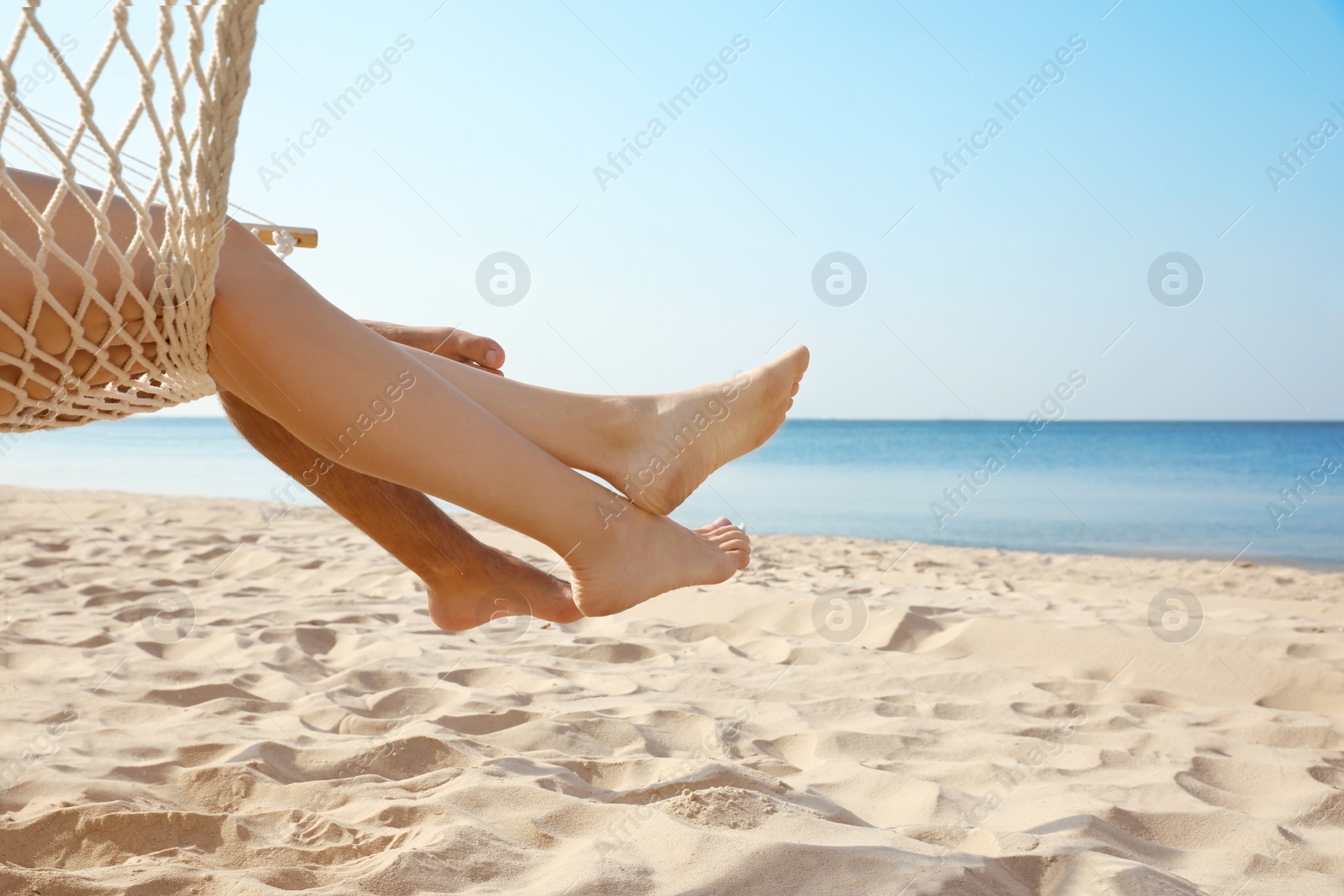 Photo of Young couple relaxing in hammock on beach, closeup