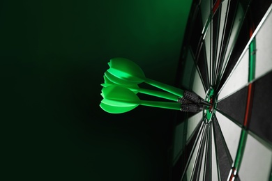 Color arrows hitting target on dart board against green background