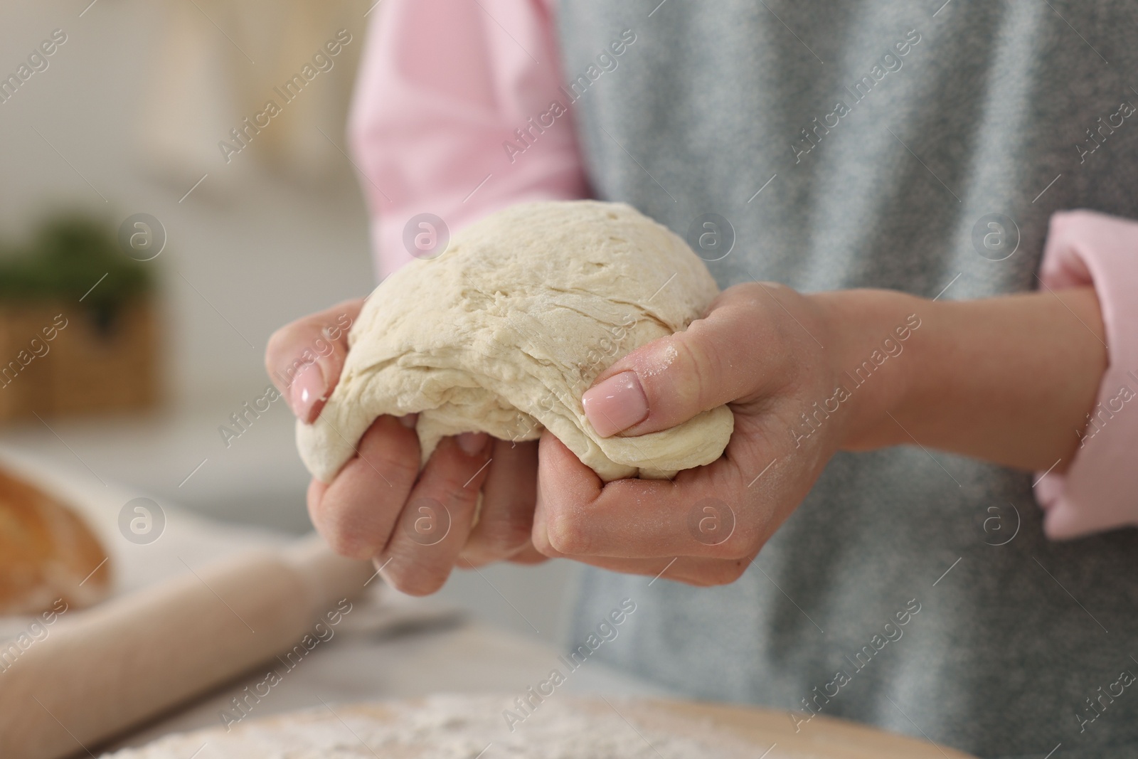 Photo of Making bread. Woman kneading dough at table in kitchen, closeup