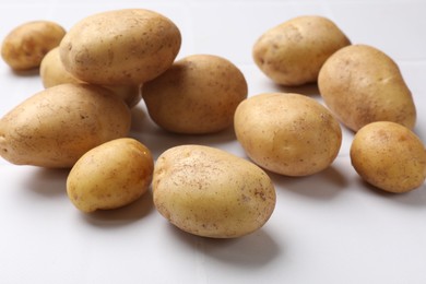 Photo of Raw fresh potatoes on white tiled table